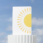 White notebook with a sun design on a white stand against a blue sky background.
