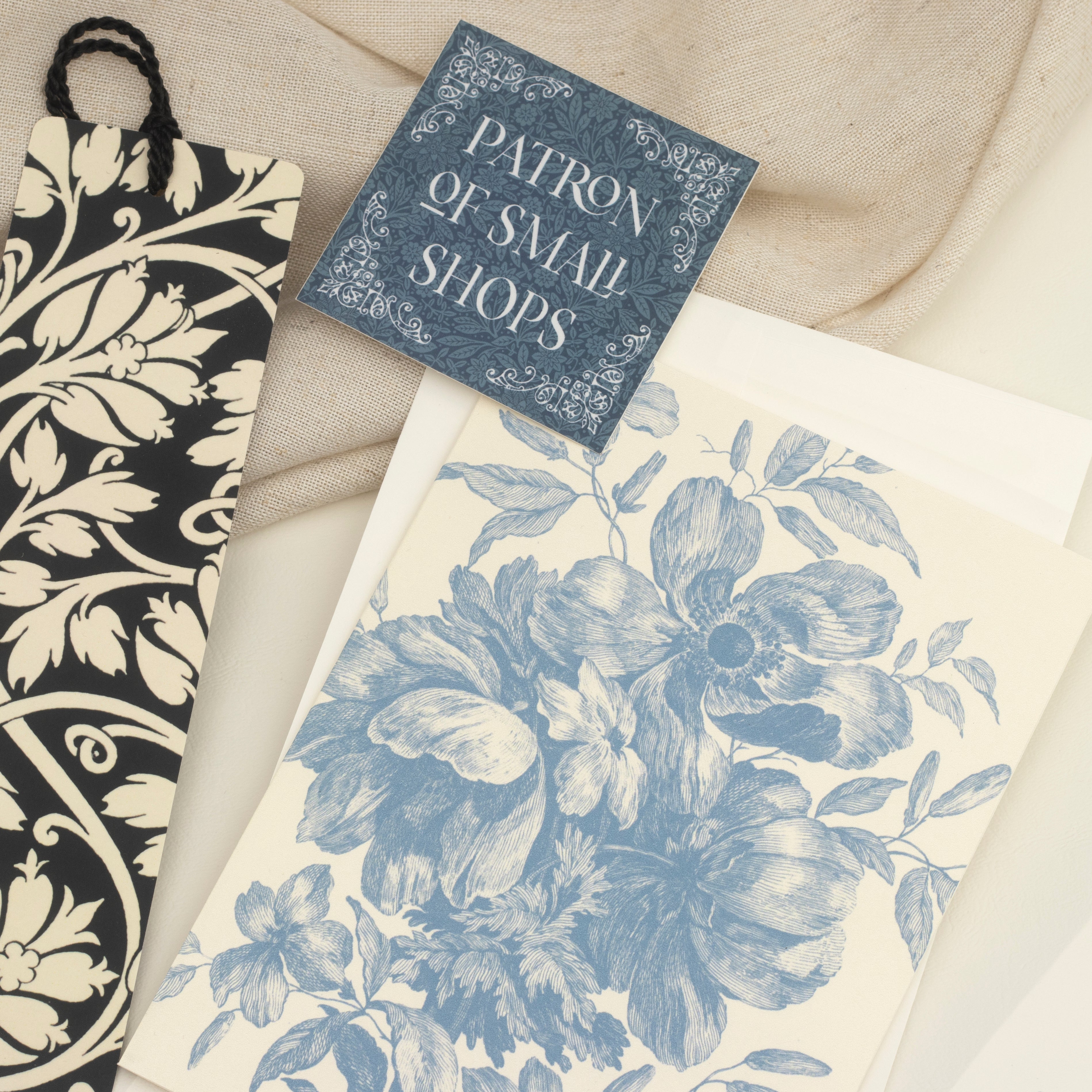 A bookmark, a blue sticker, a card, and an envelope on a neutral background.
