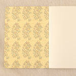An open notebook with a lemon branch pattern cover and natural white blank pages.