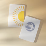 Two notebooks with sun and moon designs on a beige background