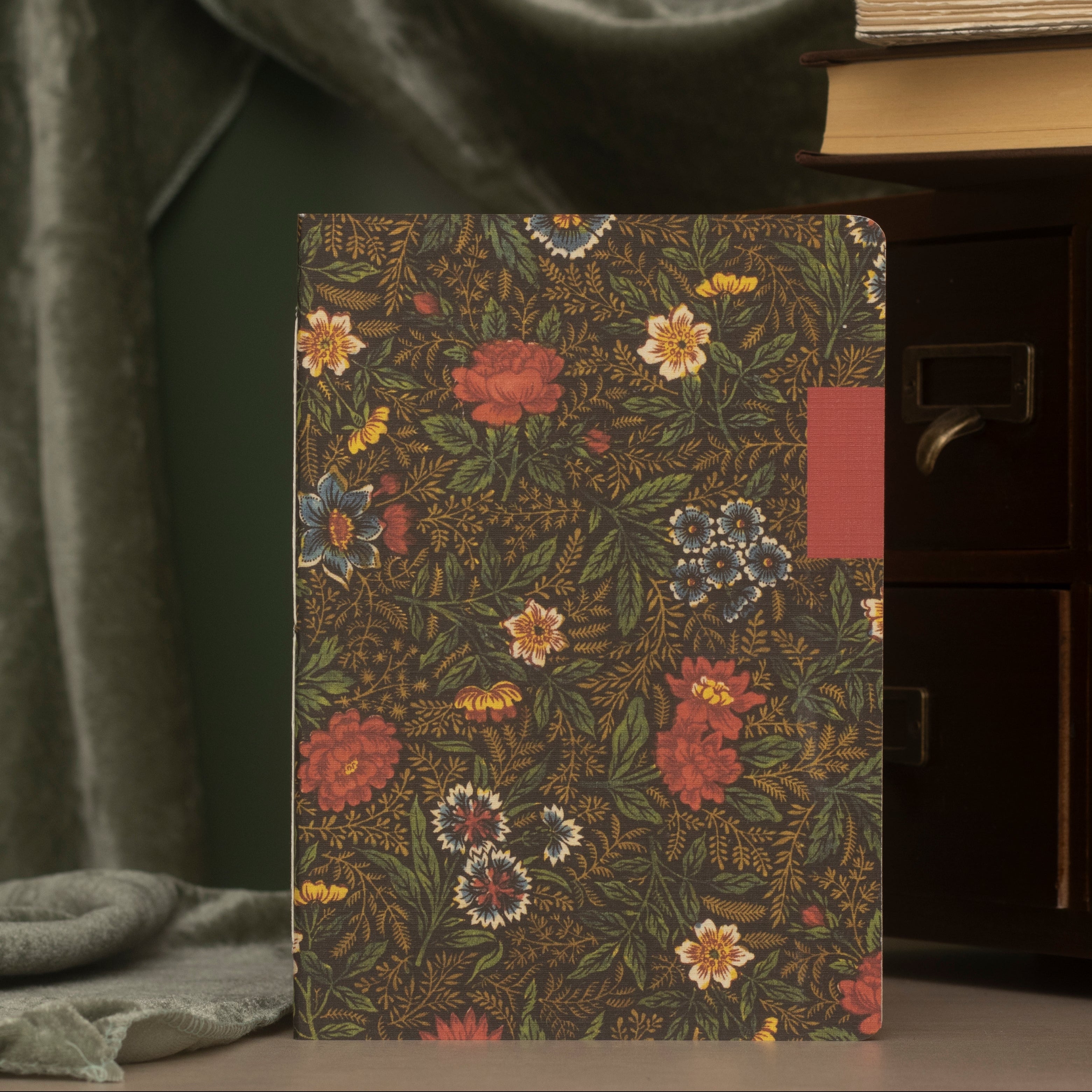 Front side of a floral-patterned notebook  on a green background.