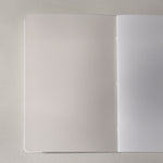 A blank notebook with one blank off-white and white page, shown open on a light gray textured surface.